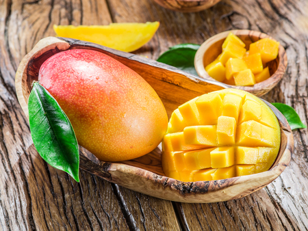 Mango fruit and mango cubes on the wooden table.の写真素材
