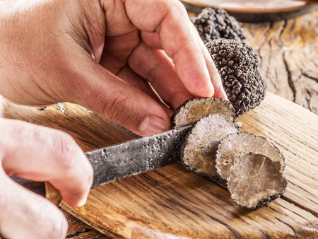 Cutting of black truffle on the wooden board.