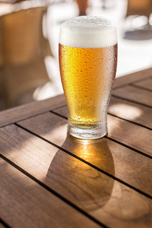 Glass of light beer on the wooden table.の写真素材