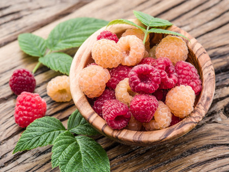 Raspberries in the wooden bowl on the table.
