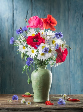 Bouquet of field flowers in the vase on the wooden table.の写真素材