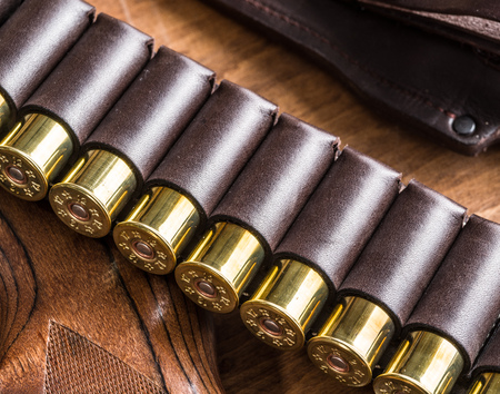 Hunting equipment - pump action shotgun, 12 guage cartridge and hunting knife on the wooden table.の写真素材