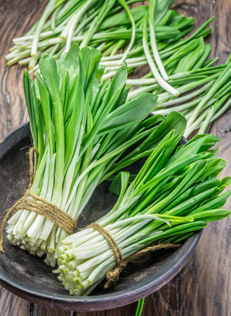 Young fresh wild garlic on the wooden table.の写真素材