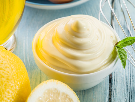 Natural mayonnaise in the white bowl and lemons.の写真素材
