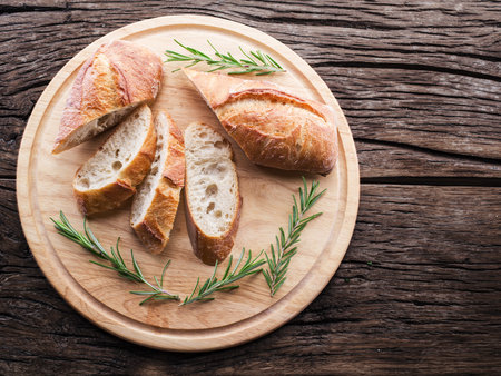 Slices of ciabatta with rosemary herb on the serving wooden tray. Top view.