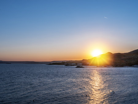 Calm sea and sunset in the cloudless orange evening sky.