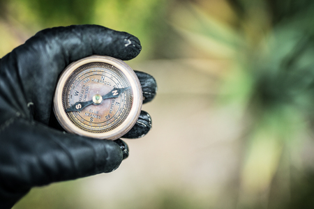 Man's hand in a leather glove holding a compass. Nature background.の写真素材