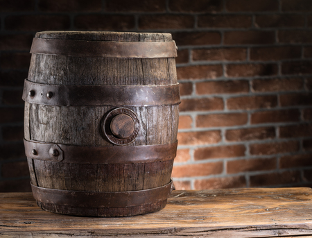 Old wooden beer cask on the table. Brick wall on the background. Craft brewery.の写真素材