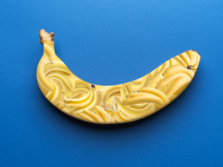 Banana on the blue background. Photo collage. Small bananas in a large banana.の写真素材