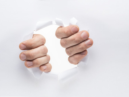 Man's hands tearing the hole on a paper.の写真素材