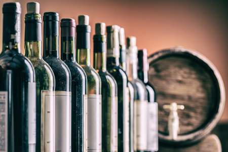 Wine bottles in row and oak wine keg.