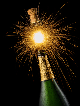 Champagne bottle with sparkler lights on the black background. Holiday background.の写真素材