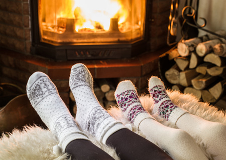 Warming and relaxing near fireplace. Woman and child feet in front of fire.  の写真素材