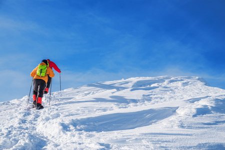 Tourists on their way to  the snow-covered mountain top. Winter hiking.の写真素材