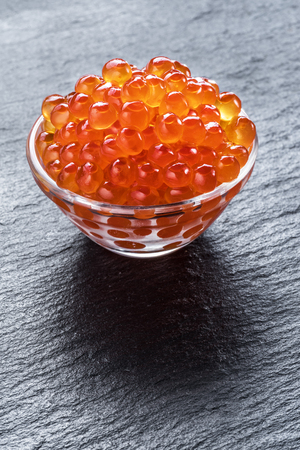 Red caviar in the bowl on gray graphite background. Macro picture.の写真素材