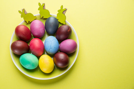 Colorful Easter eggs as an attribute of Easter celebration on the yellow plate.
