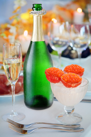 Cold bottle of sparkling wine, wine glass and red caviar over ice. Close-up.の写真素材