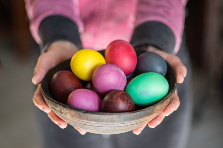 Colorful Easter eggs in bowl  in woman's hands.