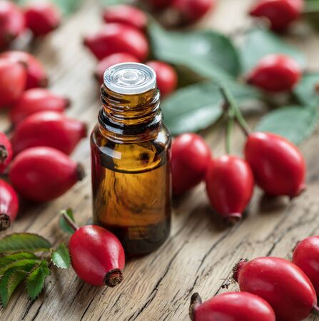 Rose-hips and rose hip seed oil on the wooden table. Close-up.の写真素材
