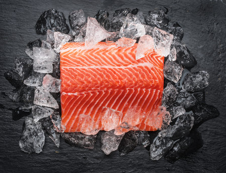 Fresh salmon fillet over ice on black cutting board. Top view.の写真素材