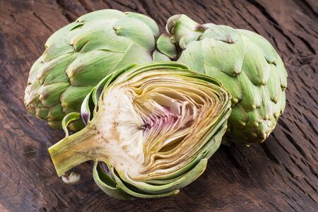 Green and purple artichoke flower edible buds on wooden background.の写真素材