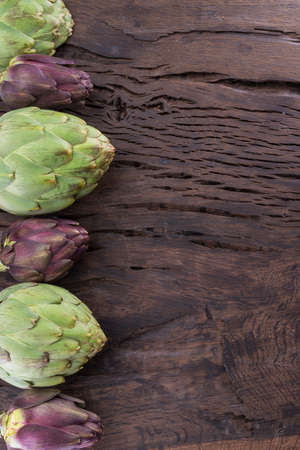 Green and purple artichoke flower edible buds on wooden background.の写真素材