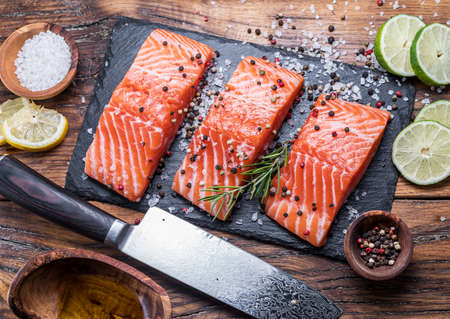 Fresh salmon fillets on black cutting board with herbs and spices. Top vew.の写真素材