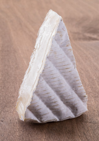 Cross section of brie cheese on wooden table. Close-up.