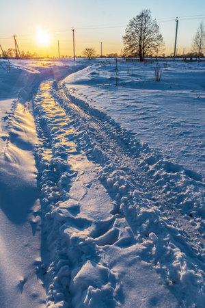 Winter out of the big city. Snowy rural winter landscape. Deep wheel track in the snow.の写真素材