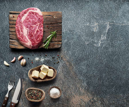 Raw beef steak with spices on the wooden board on the gray table. Top viewの写真素材