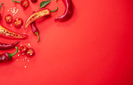 Fresh red chilli peppers and peppers slices isolated on red background. Top view.の写真素材