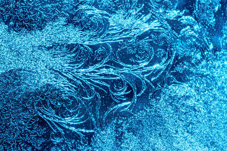 Beautiful blue frost patterns on frozen window as a symbol of Christmas wonder. Christmas or New year background.の写真素材