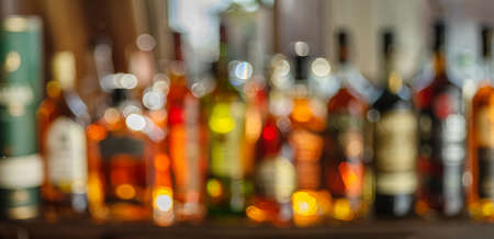 Beautiful bokeh from a row of alcoholic bottles in backlight. Panoramic shot.の写真素材