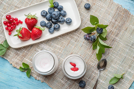 Two glass containers with plain yoghurt and berries on the table. Light summer mood.の写真素材