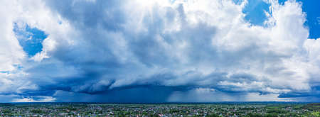 Panoramic picture of beautiful cloudscape under the village. Heavy white clouds in the blue sky.の写真素材