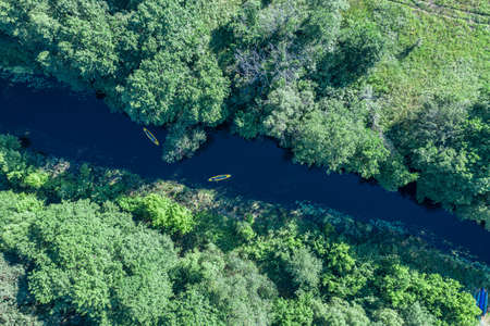 Canoes on the calm river. Aerial top view. Beautiful picture of river and green banks of the river in the summer morning day.の写真素材
