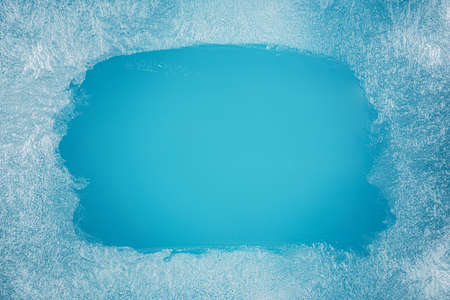 Frost patterns on frozen winter window as a symbol of Christmas wonder. In the middle of the window is a misted space for your product or lettering. Christmas or New year background.の写真素材