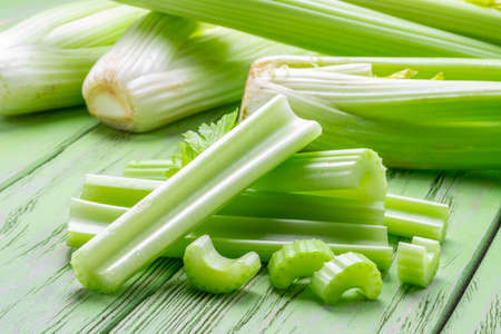 Pile of celery ribs on green wooden table. Healthy food background.の写真素材