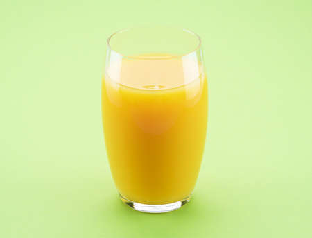 Glass of fresh orange juice isolated on light green background.の写真素材