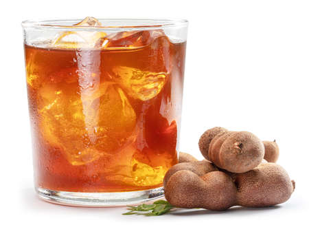 Glass of cool refreshing tamarind drink and some tamarind fruit on white background.の写真素材