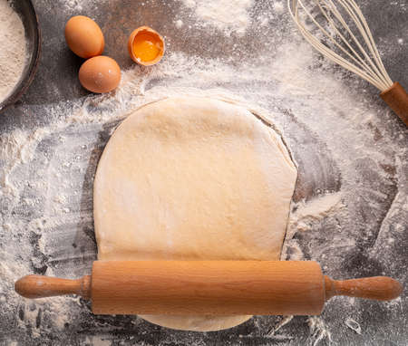 Ready to be baked dough. Top view of board, rolling pin and flour and dough.の写真素材
