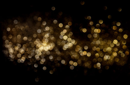 Golden blurred glitter lights on black background.