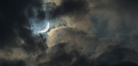 Photographer of New Moon in the cloudy gloomy night sky.
