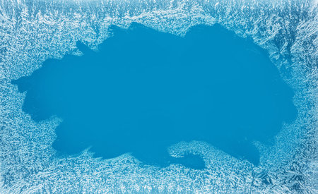 Frost patterns on frozen winter window as a symbol of Christmas wonder. In the middle of the window...