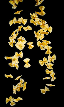 Falling dawn farfalle pasta at the balck background.