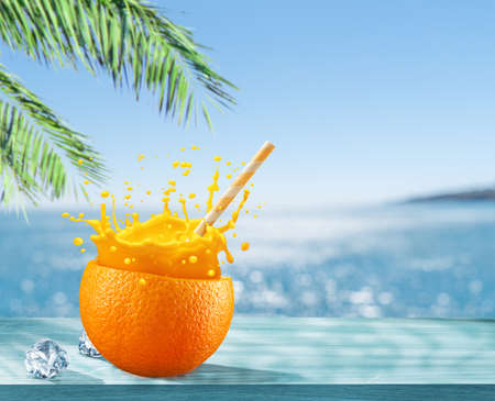 Orange fruit as the cup with orange juice splash and straw. Blue sparkling sea at the background. drink concept.の写真素材