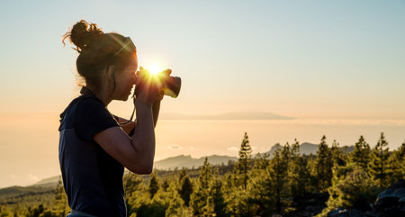 Silhouette woman with camera. Woman takes photo of La Gomera Island in the rays of the setting sun....