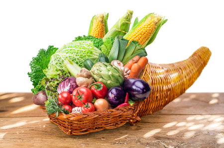 Horn of plenty with fresh organic vegetables and herbs as a symbol of autumn gifts. File contains...