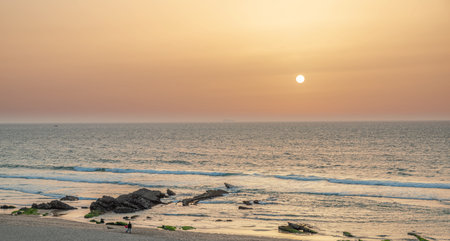 Children watching beautiful sunset at the sandy shore of the calm Atlantic ocean.の写真素材