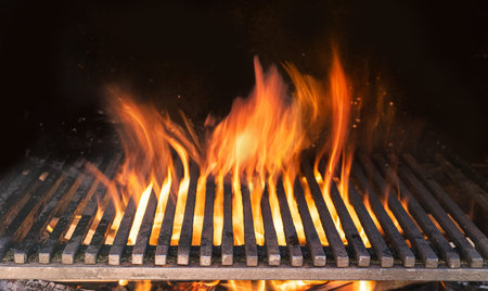 Barbecue grill with fire flames closeup on dark background.